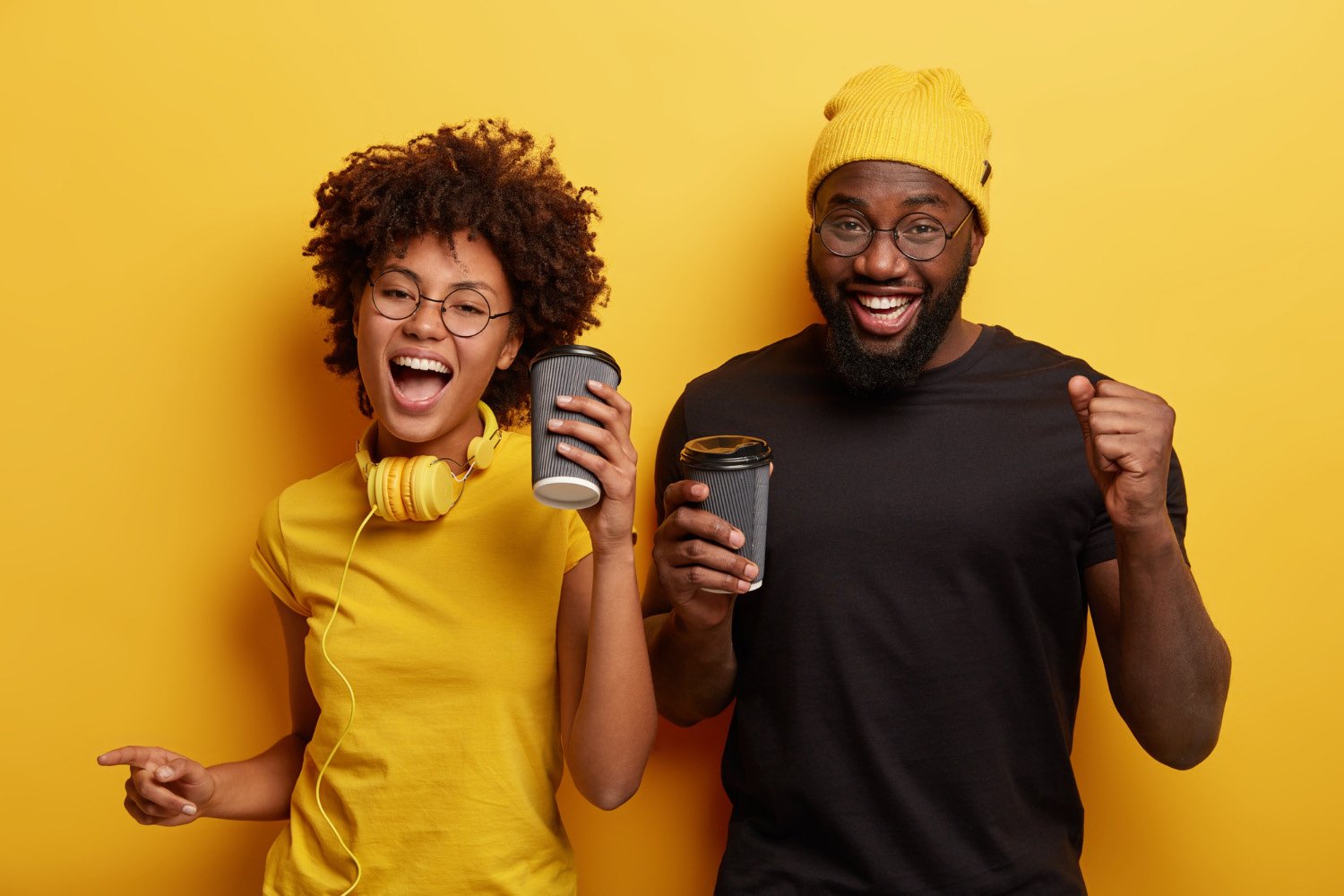 Two happy young people holding coffee cups